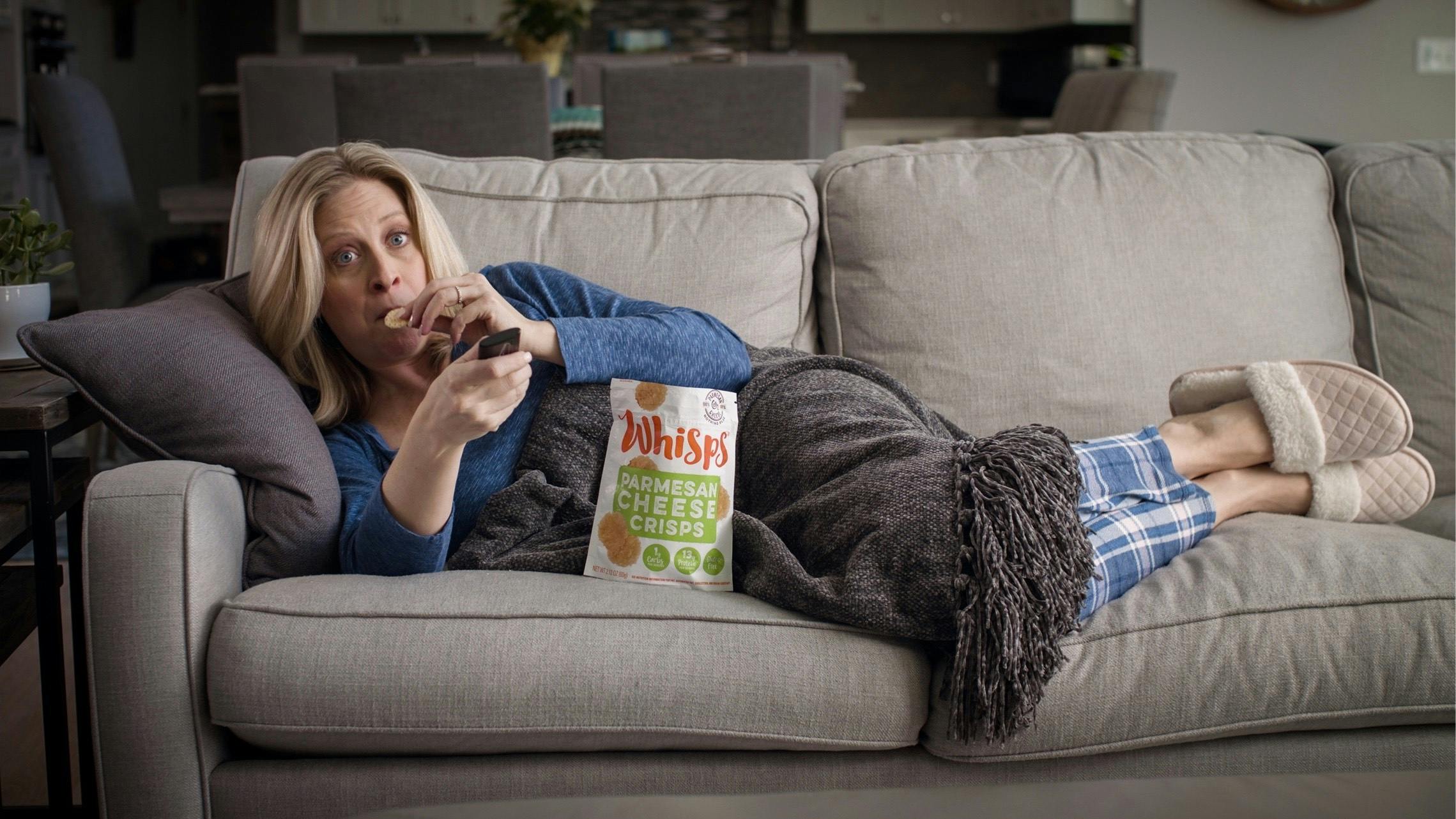 Woman lying on the couch eating Whisps.