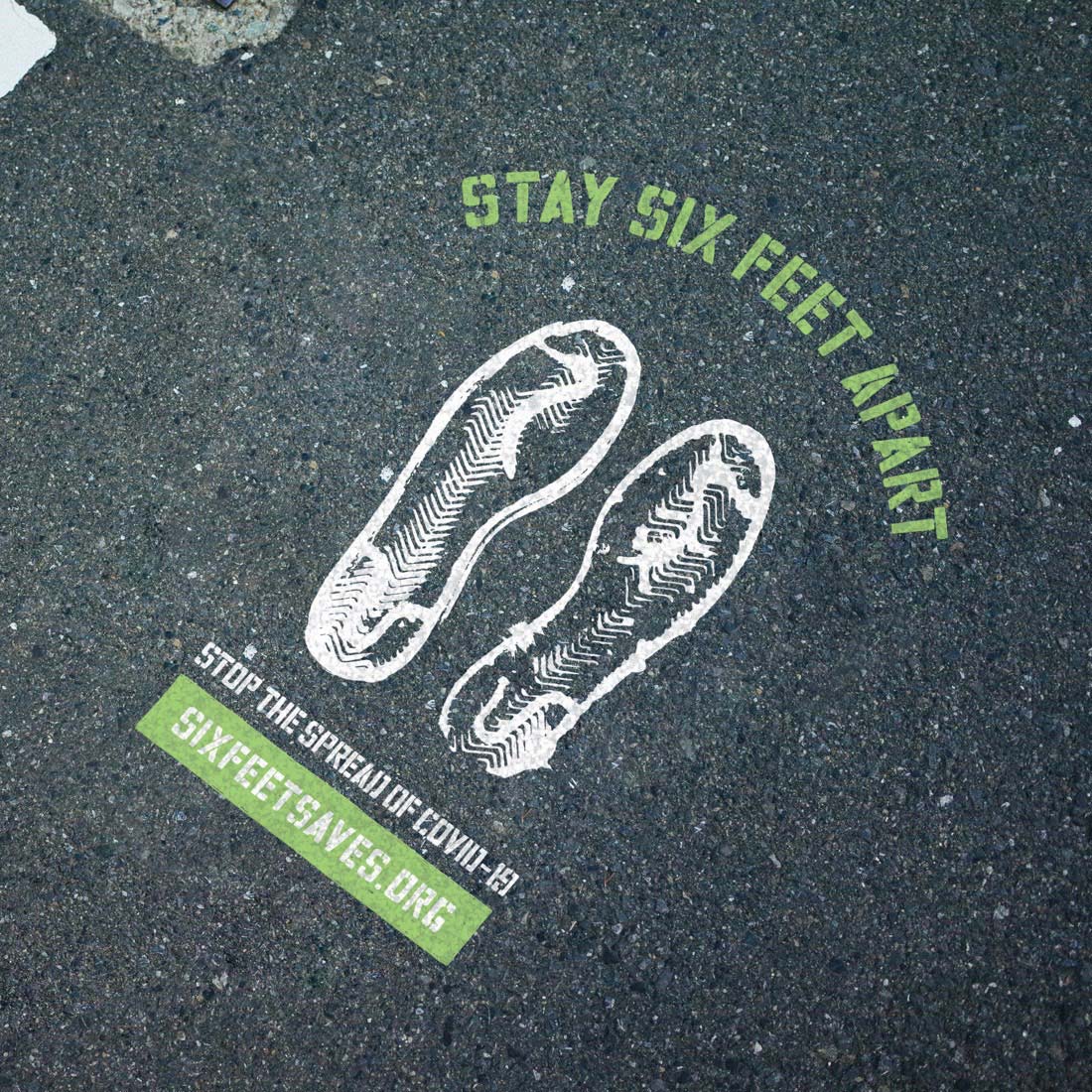Photograph of a Six Feet Saves marker spraypainted onto the concrete.